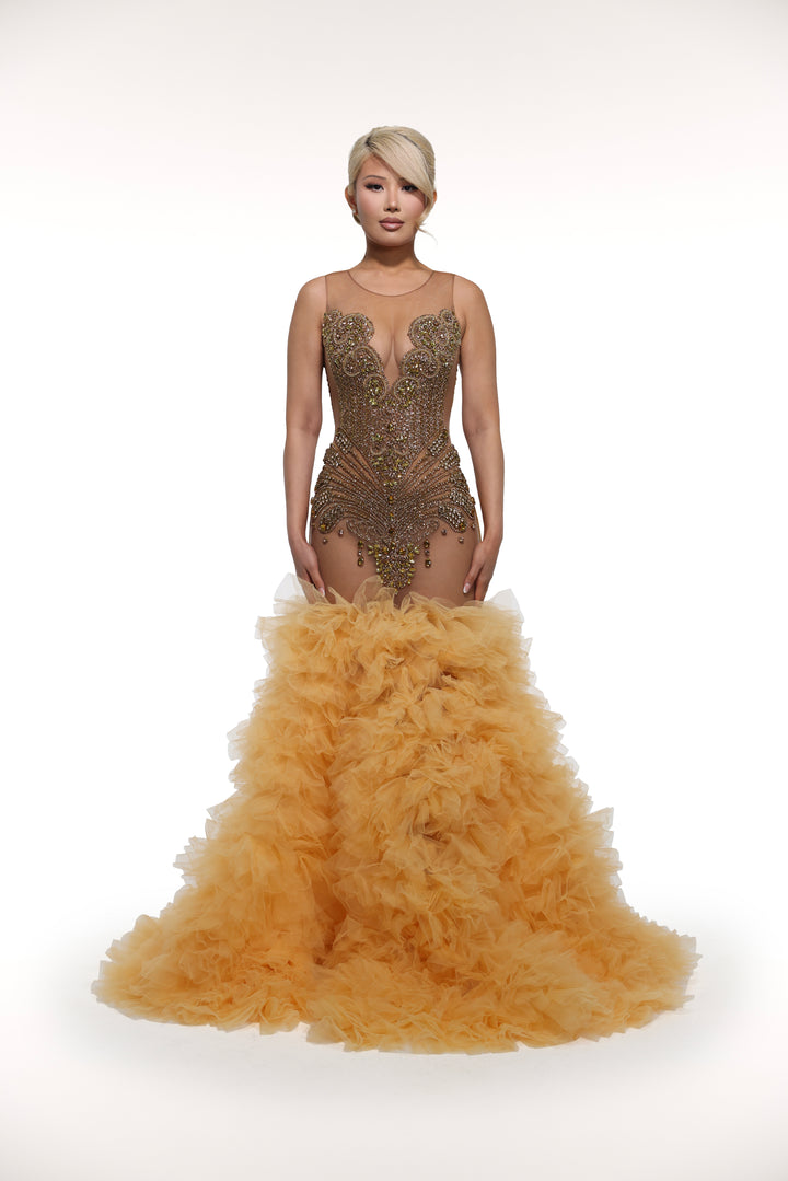 Woman wearing a gold evening gown with feathered skirt on a white background