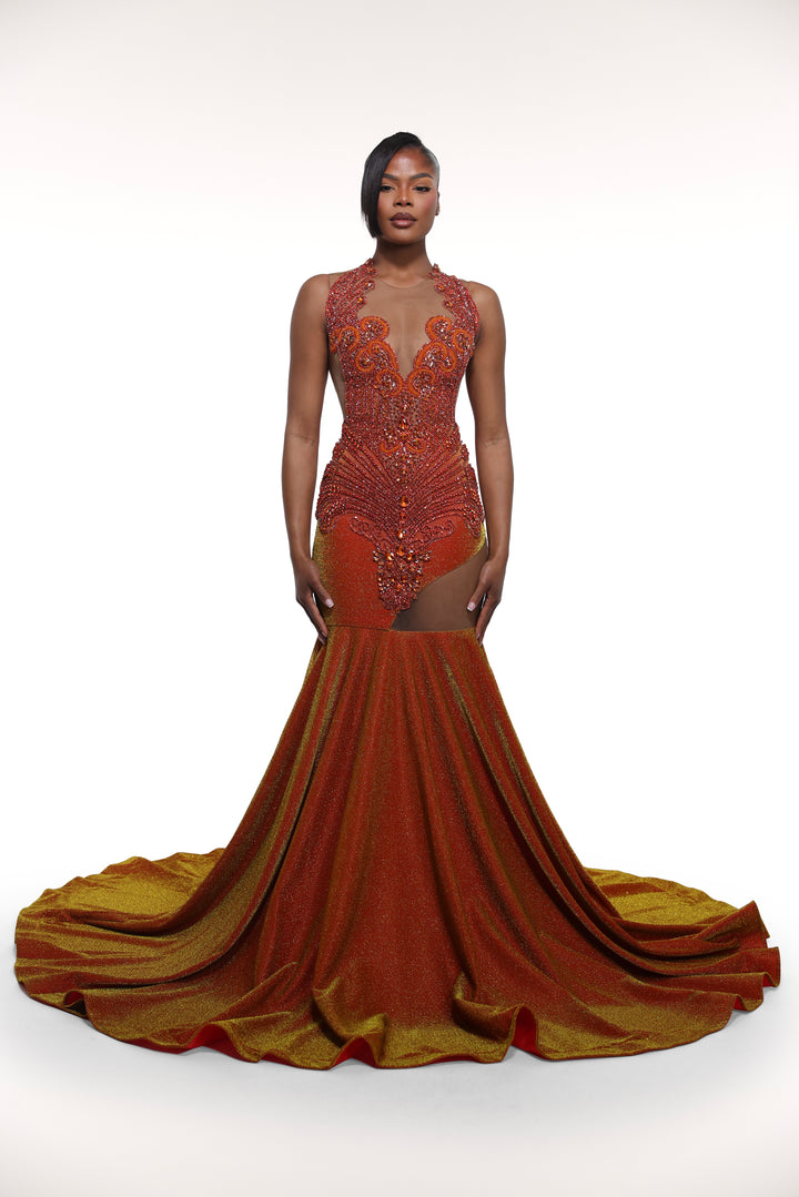 Woman wearing a rust-colored evening gown with intricate detailing on a white background